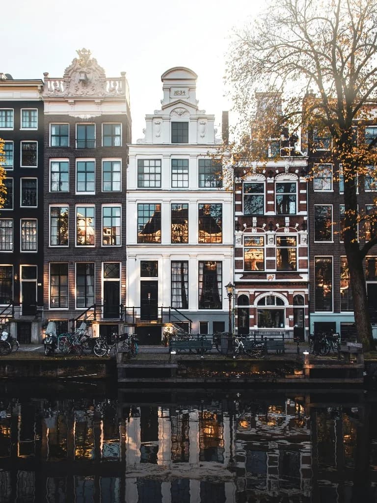 Amsterdamse grachtenpanden weerspiegeld in het water bij gouden uur